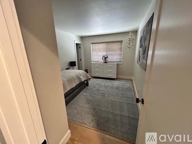 A bedroom with a bed, dresser, and window with blinds.