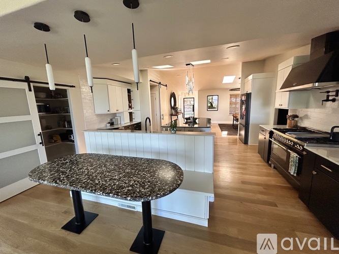 A modern kitchen with a granite table and black stove.