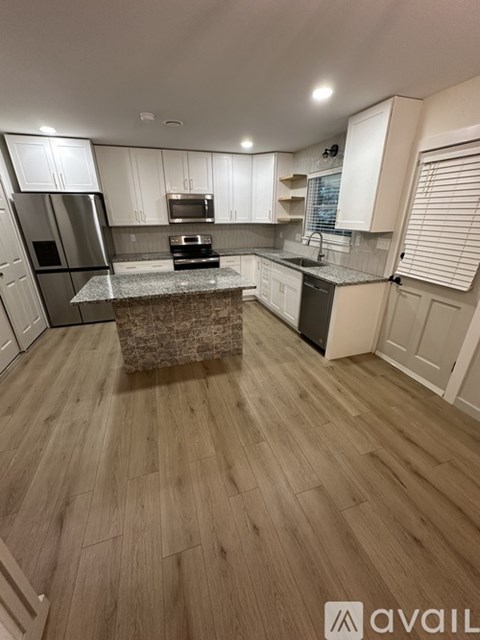 A kitchen with wooden floors and white cabinets.