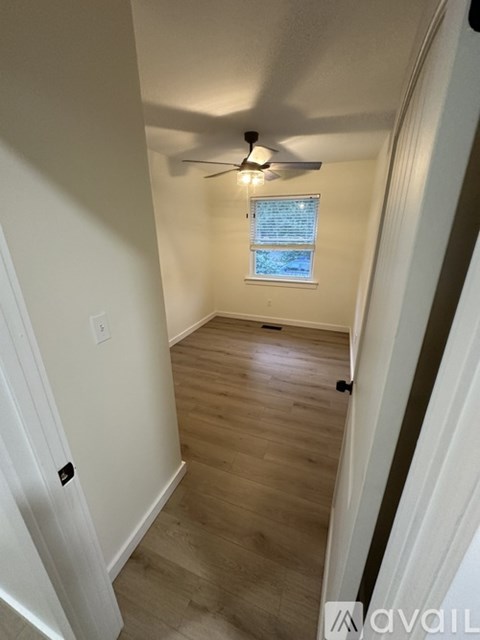 A room with a ceiling fan and a window with blinds.