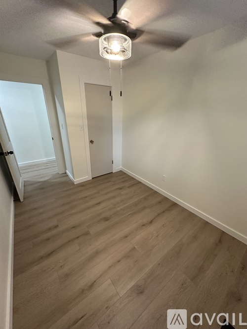 A room with a ceiling fan and wooden flooring.
