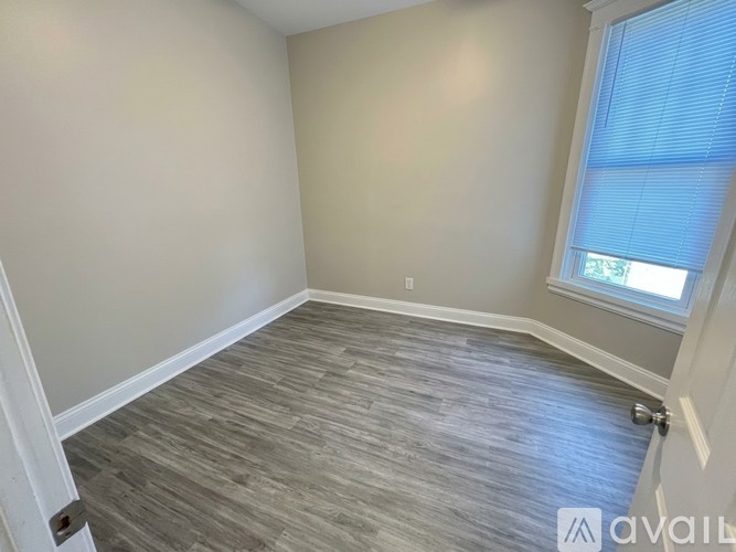 A room with a wooden floor and a window with blinds.