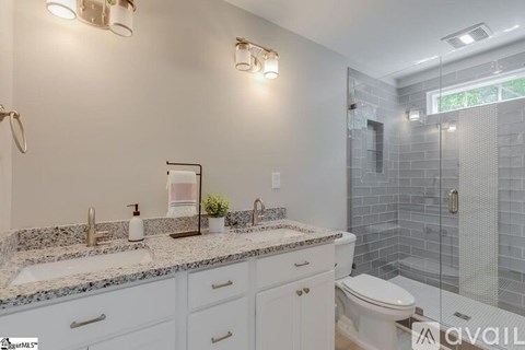 A bathroom with a granite countertop and a glass shower stall.