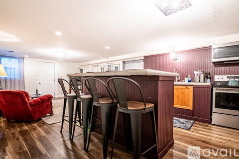 A kitchen with a red chair and wooden floors.