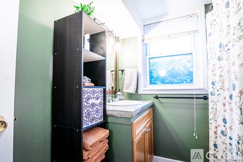 A bathroom with a green wall and a window.
