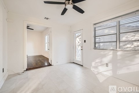 A spacious room with a ceiling fan and a door leading to another room.
