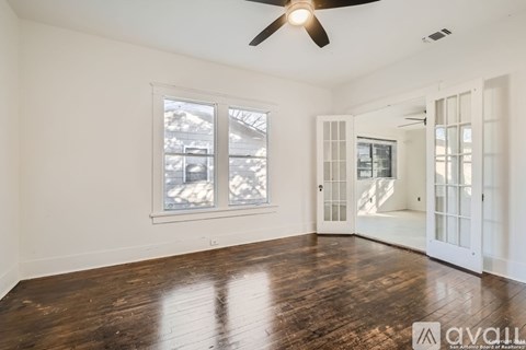 A spacious room with a ceiling fan and wooden flooring.