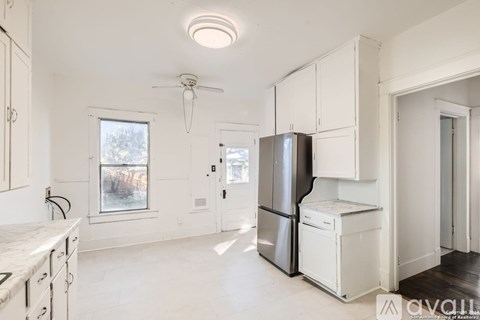 A kitchen with white cabinets and a refrigerator.