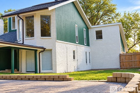 A white house with a green roof and a grey garage door.