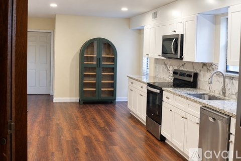 A kitchen with white cabinets and a wooden floor.