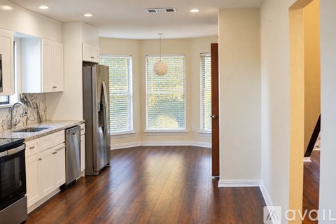 A kitchen with white cabinets and a wooden floor.