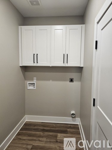 A room with white cabinets and a wooden floor.
