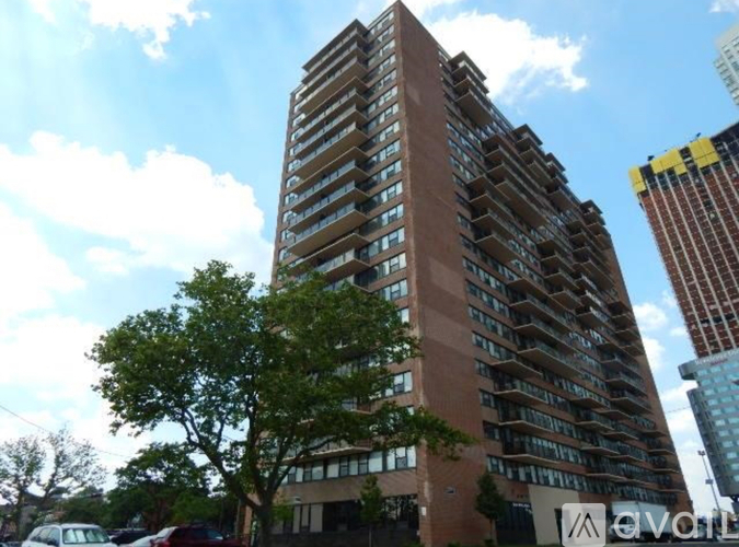 A tall apartment building with a sign that reads "Avail" in front of it.