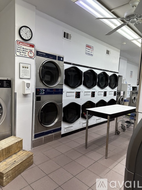A laundry room with a row of washing machines and a table.