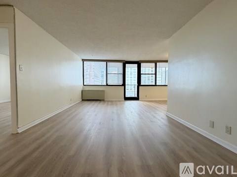 A spacious room with wooden flooring and a large window.
