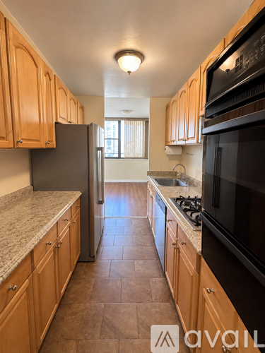 A kitchen with wooden cabinets and a black microwave.