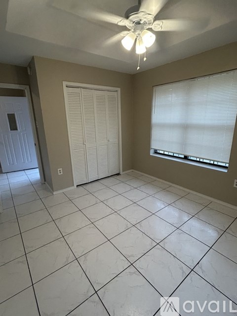 A room with a ceiling fan and tiled flooring.
