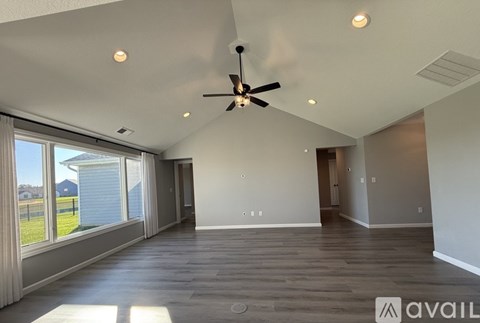 A spacious room with a ceiling fan and large windows.
