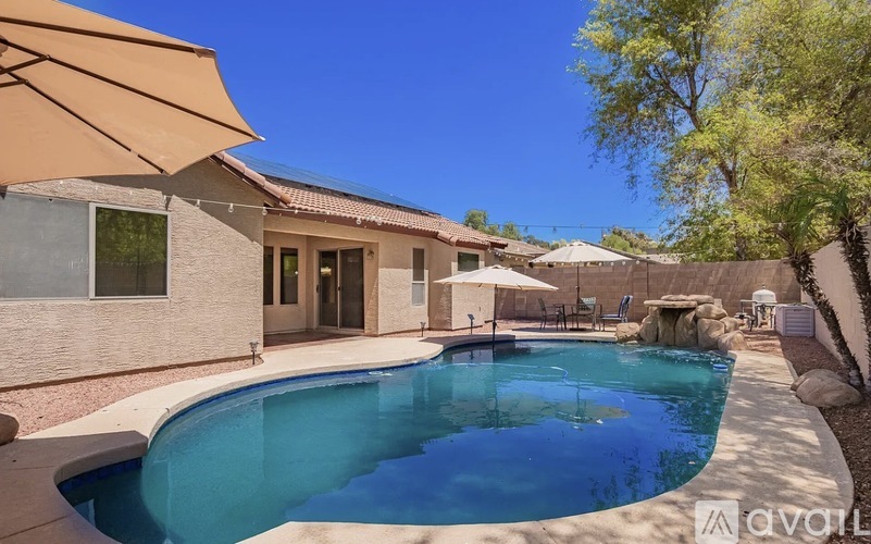 A swimming pool in a backyard with a patio and a house in the background.
