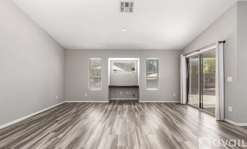 A spacious room with wooden flooring and a large window.