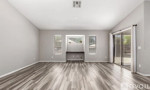 A spacious room with wooden flooring and a large window.