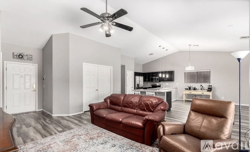 A living room with a red leather couch and a ceiling fan.