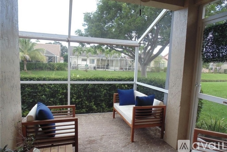 A patio with a couch and a chair with a view of a backyard.