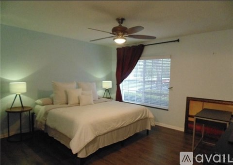A bedroom with a bed, a ceiling fan, and a window with curtains.