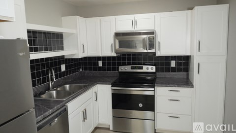 A kitchen with white cabinets and black countertops.