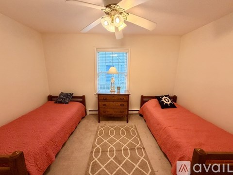 A bedroom with two beds and a ceiling fan.
