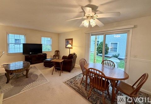 A living room with a television, a table and chairs, and a ceiling fan.