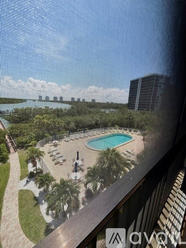 A pool area with a view of the water and buildings.