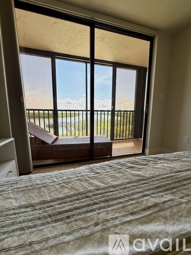 A bedroom with a large bed and a view of the outdoors through a sliding glass door.