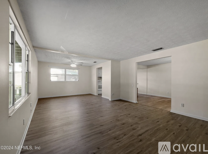 A spacious room with wooden floors and white walls.