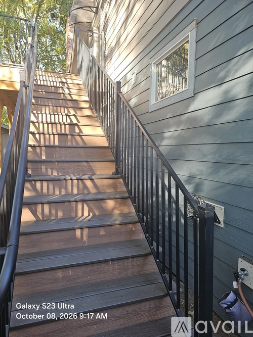 A staircase with a metal railing and wooden steps leading up to a window.