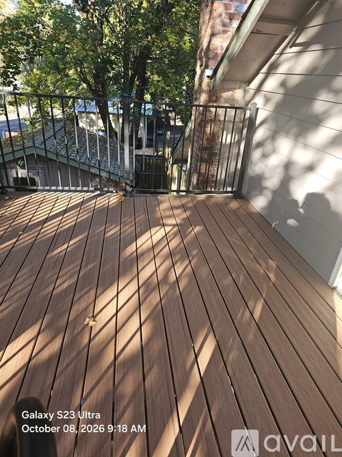 A wooden deck with a metal railing and trees in the background.