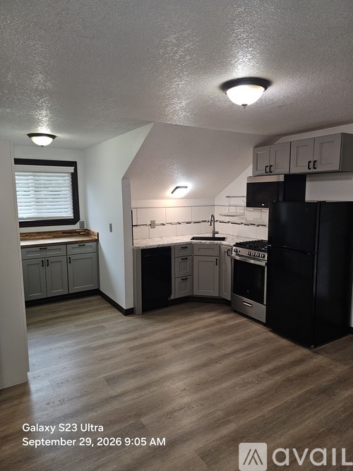 A kitchen with black appliances and wooden floors.