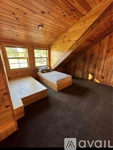 A bedroom with wooden walls and a bed with a mattress and pillows.