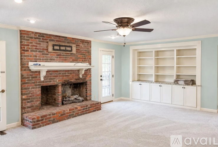 A living room with a brick fireplace and a ceiling fan.