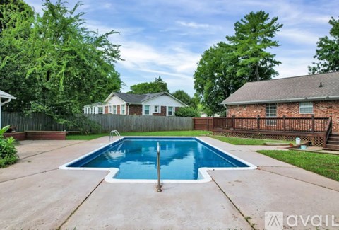A backyard with a pool and a house in the background.