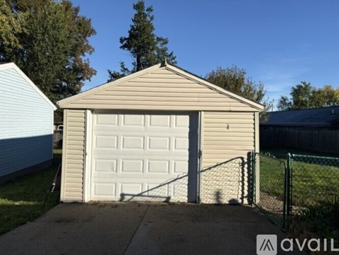 A small garage with a white door is situated in a residential area.