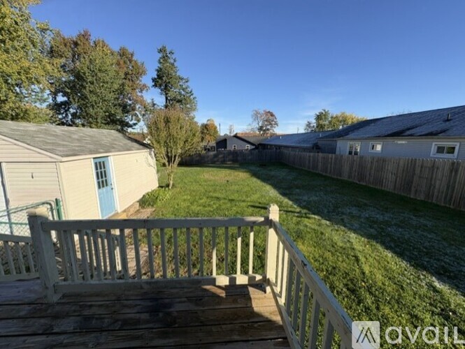 A wooden deck leads to a backyard with a fence and a shed.