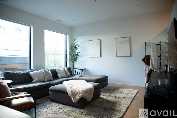 A living room with a grey couch and a rug.