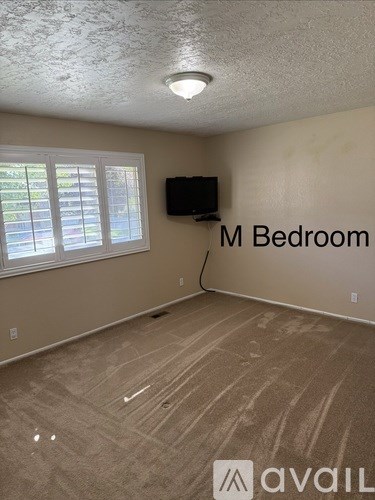 A bedroom with a carpeted floor and a window with blinds.