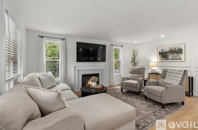 A living room with a fireplace, two chairs, and a couch.