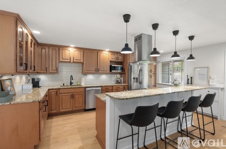 A kitchen with wooden cabinets and a white island with black chairs.