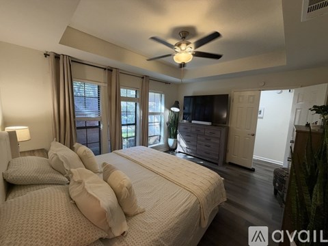 A well-lit bedroom with a large bed and a ceiling fan.