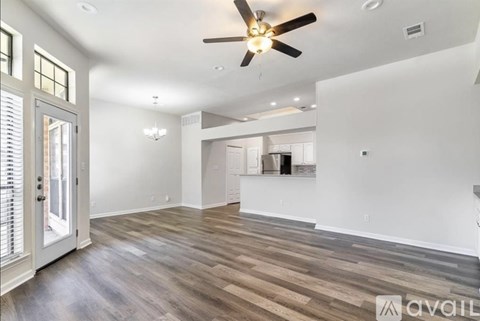 A spacious room with a ceiling fan and wooden flooring.
