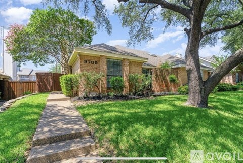 A house with the number 8709 on it is surrounded by a green lawn and trees.
