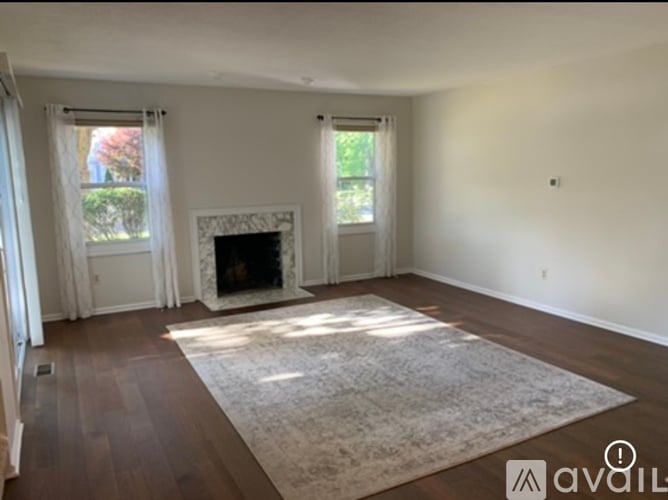 A living room with a fireplace and a rug in the middle.